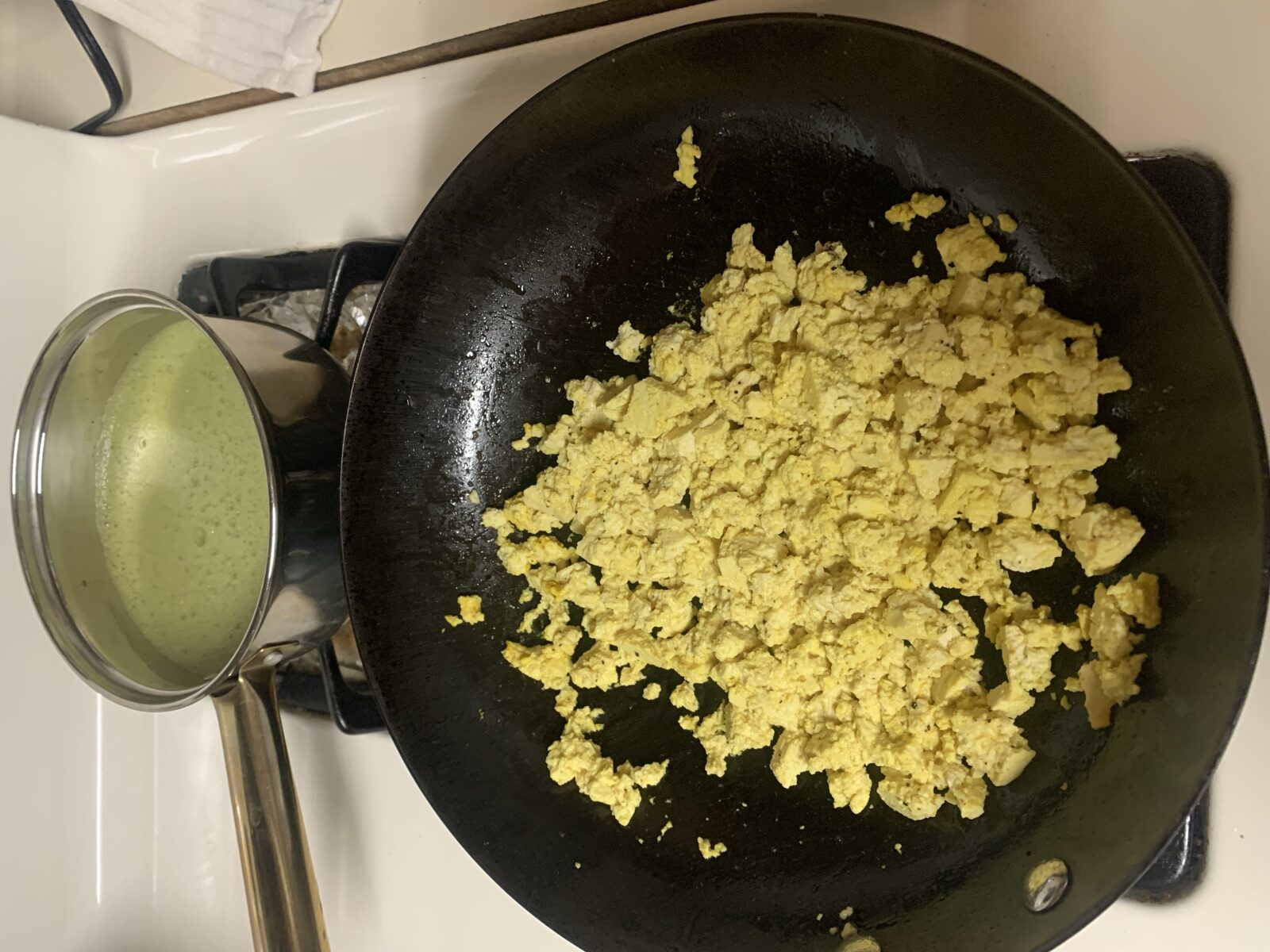 Frothy matcha green tea beside a turmeric tofu scramble in a cast-iron skillet — MediterAsian preparations rich in EGCG, curcumin, and soy isoflavones