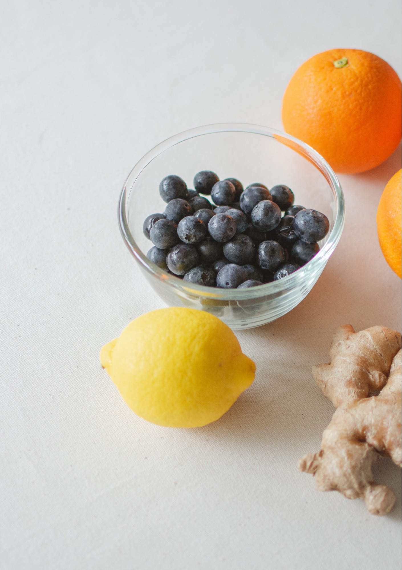 A bowl of blueberries sits with oranges, lemon, and ginger to illustrate polyphenol-rich foods.